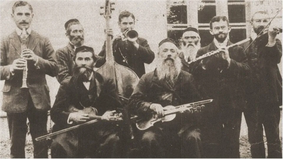 A 1912 photograph of a family klezmer band from Rohatyn, in Galicia: men with beards and dark jackets hold a clarinet, a flute, violins, a double bass and a brass horn.